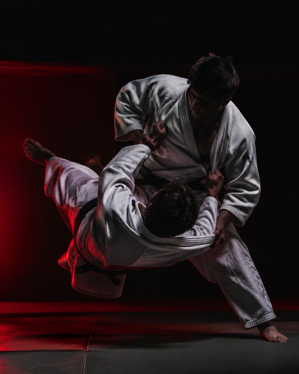 Due judoka in judogi eseguono una proiezione sul tatami della Bellatorum Gym